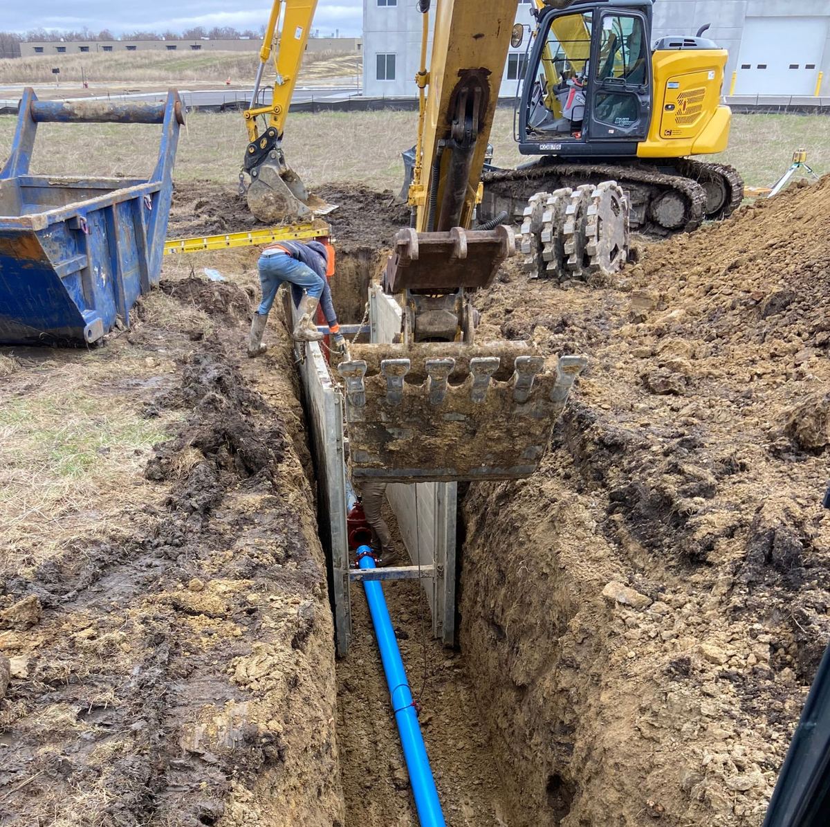 Water main installation in an open trench with excavator